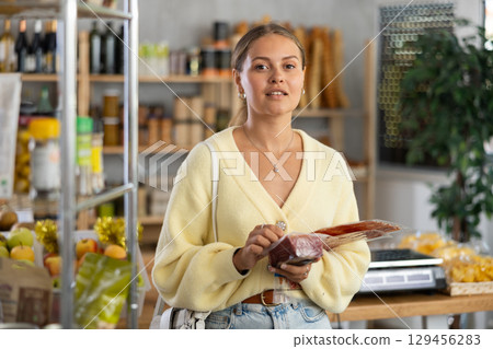 Woman choosing dried sausage and meat in the store 129456283