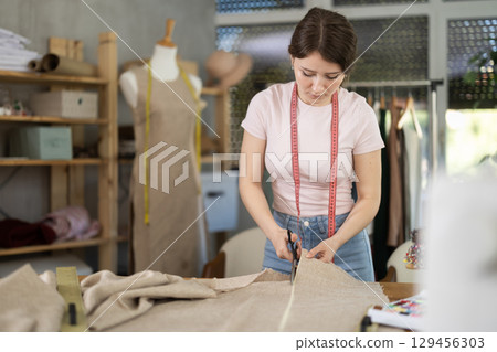 Woman professional working cut material at sewing atelier 129456303