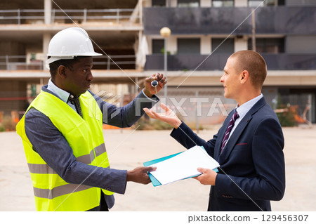 Man reciveing keys to new apartment from engineer Man reciveing keys to new apartment from engineer 129456307