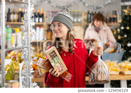 Adolescence girl customer choose consider desserts and sweet snacks, woman in background 129456329