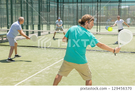 Men play padel on an outdoor tennis court. Hitting the ball with racket Men play padel on an outdoor tennis court. Hitting the ball with racket 129456370