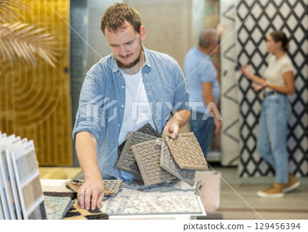 Young man choosing carpet samples in store 129456394
