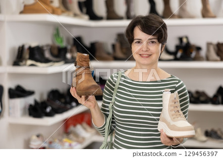 Woman takes samples from showcase and examines shoes Woman takes samples from showcase and examines shoes 129456397