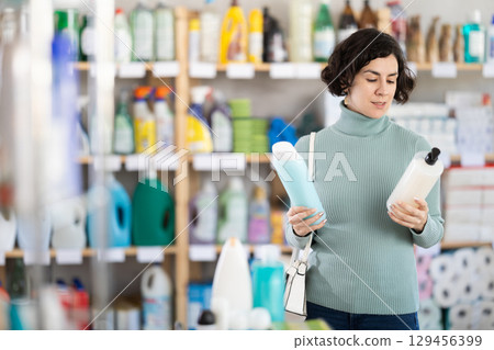 Middle-aged woman choosing shampoo or shower gel at supermarket 129456399