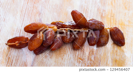 Branch of ripe dried dates on wooden background 129456407