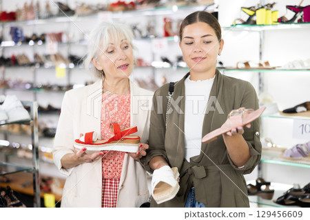Elderly woman consults a young woman to buy summer shoes 129456609