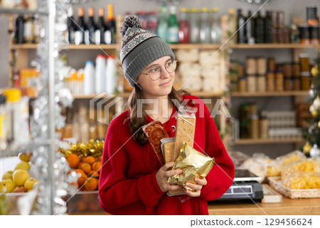 Adolescence girl customer choose consider desserts and sweet snacks. Adolescence girl customer choose consider desserts and sweet snacks. 129456624
