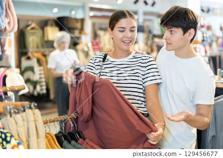 Young couple choosing convenient hoodie in clothing store 129456677
