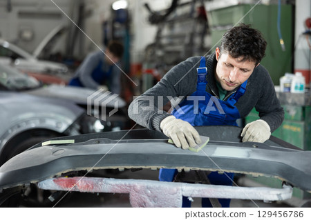 Man auto mechanic handle polishes body parts Man auto mechanic handle polishes body parts 129456786
