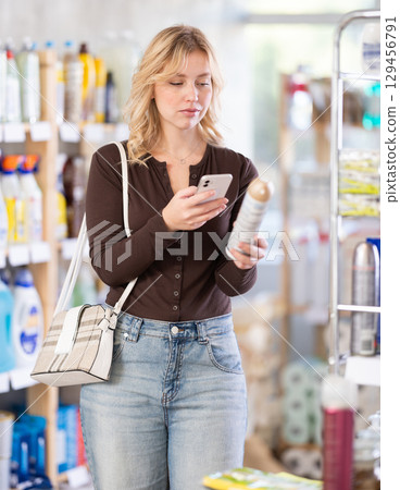 Before making purchase, girl buyer scan QR code on packaging of room spray aerosol Before making purchase, girl buyer scan QR code on packaging of room spray aerosol 129456791