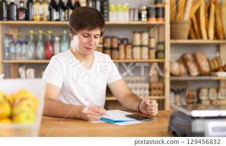 Young male salesman making notes in documents Young male salesman making notes in documents 129456832
