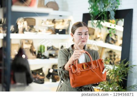 Young woman choosing handbag in store Young woman choosing handbag in store 129456871