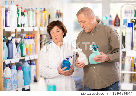Couple man and woman choosing cleaning spray in store Couple man and woman choosing cleaning spray in store 129456944