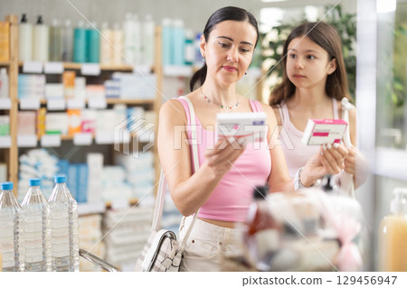 Woman buyer with teen daughter select paracetamol tablets in drug store Woman buyer with teen daughter select paracetamol tablets in drug store 129456947
