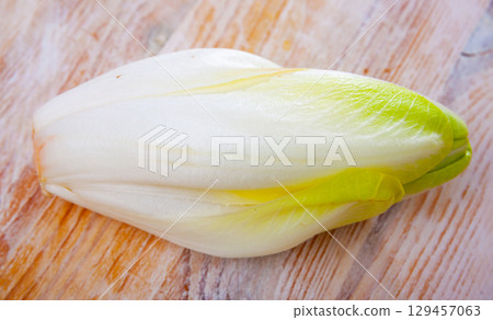 Head of belgian endive chicory on wooden table 129457063