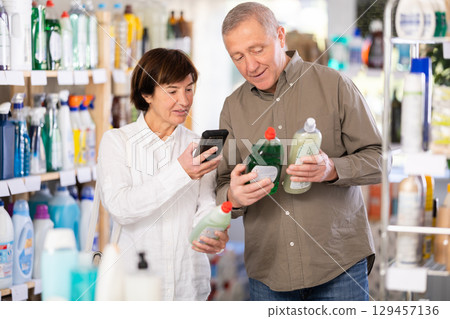woman scans the barcode and shows her elderly husband the price of household chemicals woman scans the barcode and shows her elderly husband the price of household chemicals 129457136