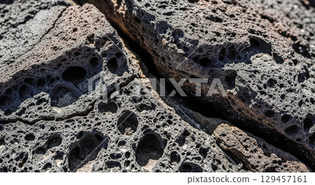 Abstract texture background showing closeup of dark volcanic rock with crack, geology concept with porous lava stone surface for wallpaper or design element 129457161