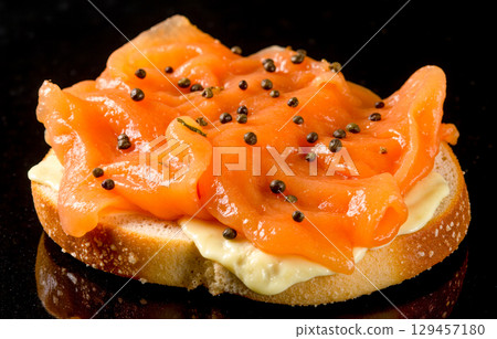 Gourmet appetizer with smoked salmon and cream cheese on toasted bread, delicious canape on black background for restaurant menu concepts Gourmet appetizer with smoked salmon and cream cheese on toasted bread, delicious canape on black background for restaurant menu concepts 129457180
