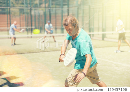 Male player serving ball during training padel in court 129457196