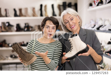 Adult and elderly women choosing boots in store 129457263