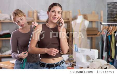 Woman tailor taking measurements from client to sew clothes Woman tailor taking measurements from client to sew clothes 129457294