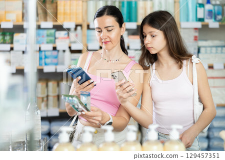 Mom and daughter client scanning barcode on toothbrush in drugstore 129457351
