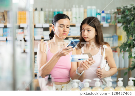 Mom and daughter customer scanning QR-code on ointment box 129457405