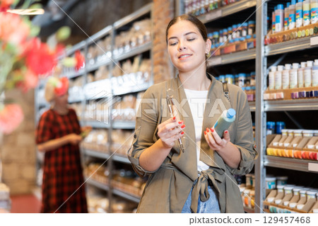 Female customer chooses multi-colored pigments for her future earthenware or ceramic tableware in specialty store Female customer chooses multi-colored pigments for her future earthenware or ceramic tableware in specialty store 129457468