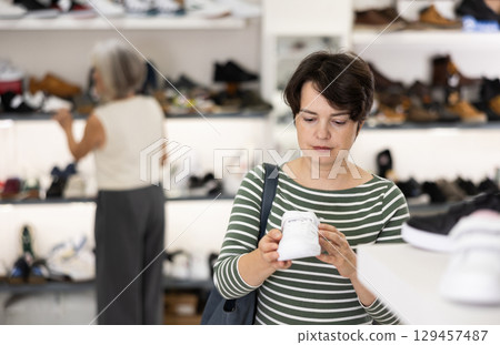 Adult woman chooses sneakers in shoe store 129457487