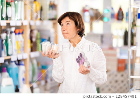 Elderly woman choosing scented candles in store Elderly woman choosing scented candles in store 129457491
