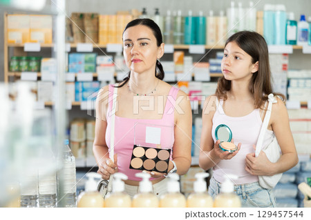 Mom and daughter choosing cosmetics in chemist's shop Mom and daughter choosing cosmetics in chemist's shop 129457544