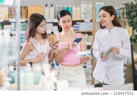 Mother and daughter scan ointment qr code with pharmacist 129457551