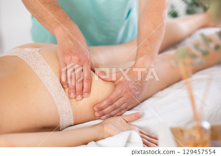Woman lies and enjoys during anti-cellulite massage in buttocks Woman lies and enjoys during anti-cellulite massage in buttocks 129457554