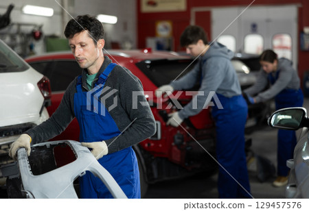 Service station man employee works in repair box, department 129457576