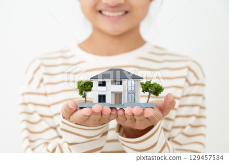 一位國中女生微笑地拿著房屋模型 129457584