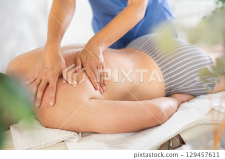 Female masseur works out shoulder problem area for male athlete client. Close-up Female masseur works out shoulder problem area for male athlete client. Close-up 129457611