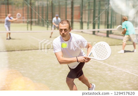 Adult and young men playing padel against two men Adult and young men playing padel against two men 129457620