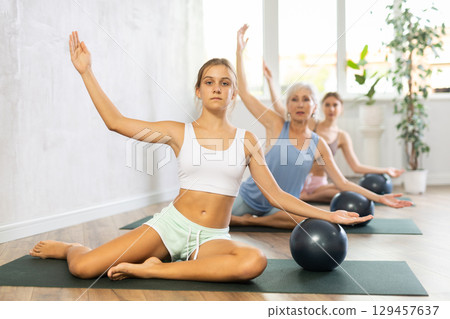 Teenage girl doing pilates with soft ball in group 129457637