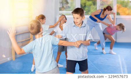 Boys and girls in gym perform basic elements of krav maga self-defense system. 129457673