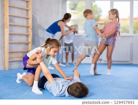 Girls and boys of performing protection with wring hands during training in self-defense 129457691