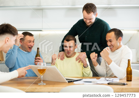 Happy male friends exulting after successful virtual investment Happy male friends exulting after successful virtual investment 129457773