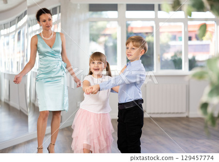 Tween boy and girl performing waltz in pair in dance hall 129457774