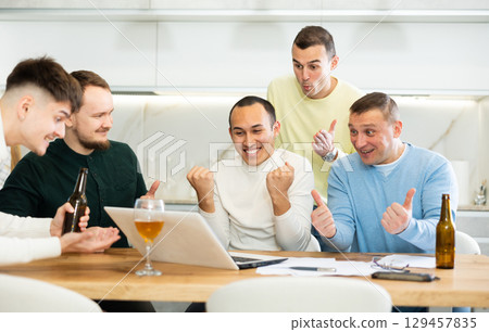 Happy male friends exulting after successful virtual investment Happy male friends exulting after successful virtual investment 129457835