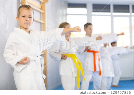 Children students repeat position and perform sequence of punches and painful techniques kata Children students repeat position and perform sequence of punches and painful techniques kata 129457856