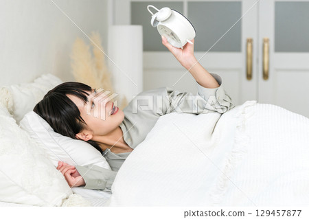 年輕的亞洲女性看到鬧鐘時感到驚訝和驚訝(睡過頭、遲到、睡過頭) 年輕的亞洲女性看到鬧鐘時感到驚訝和驚訝(睡過頭、遲到、睡過頭) 129457877