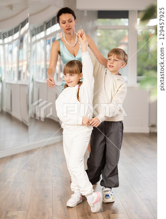 Preteen boy and girl refining slow foxtrot technique in dance hall Preteen boy and girl refining slow foxtrot technique in dance hall 129457925