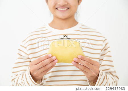 一名國中生拿著一個黃色扣式錢包 一名國中生拿著一個黃色扣式錢包 129457983