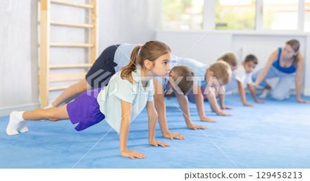 Group of little children doing push-ups on sports mats during a self-defense class in gym 129458213