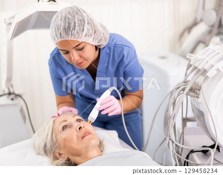 Old woman having face radiolifting procedure 129458234