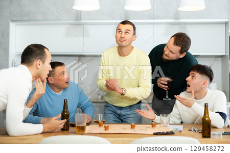 Cheerful men playing drinking board game at bachelor gathering 129458272